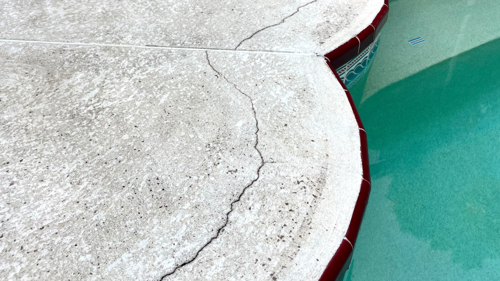 Crack in concrete along an in-ground pool.