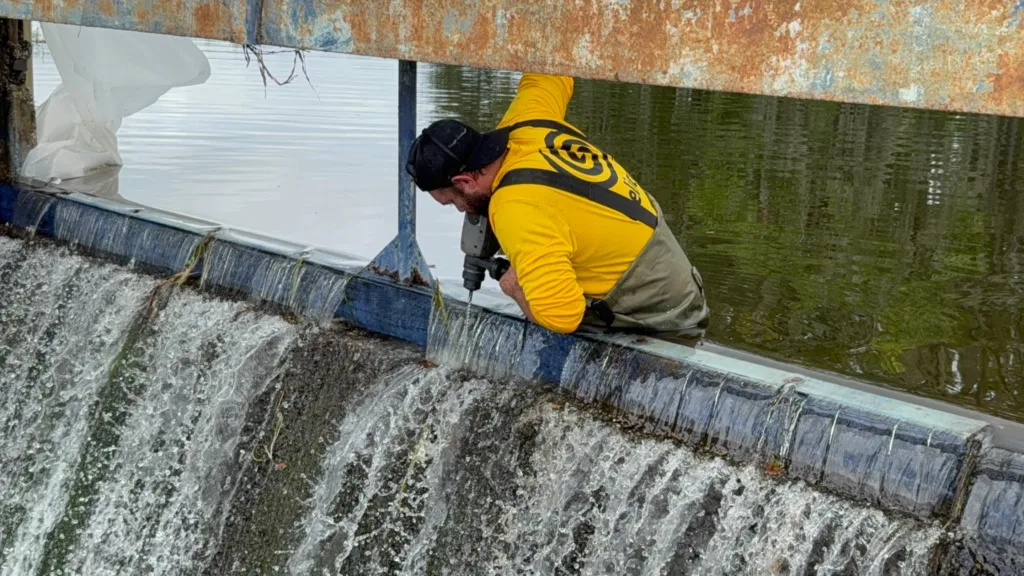 Technician performing polyurethane grout injection drilling on spillway structure for dam repair in Winter Haven, FL.