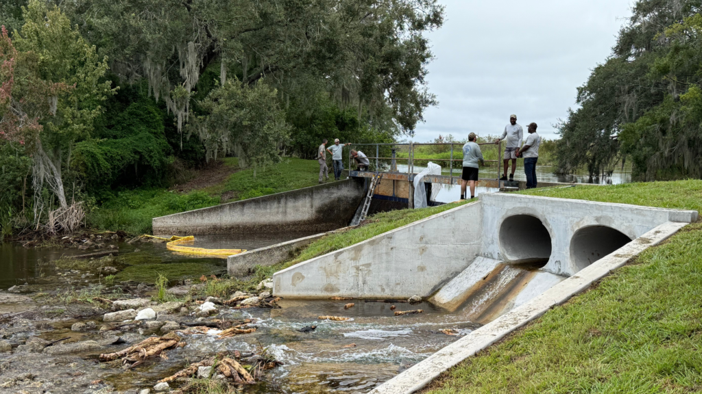 Wide view of Lake Lulu dam, spillway, and culvert system in Winter Haven, FL during soil stabilization and repair project.