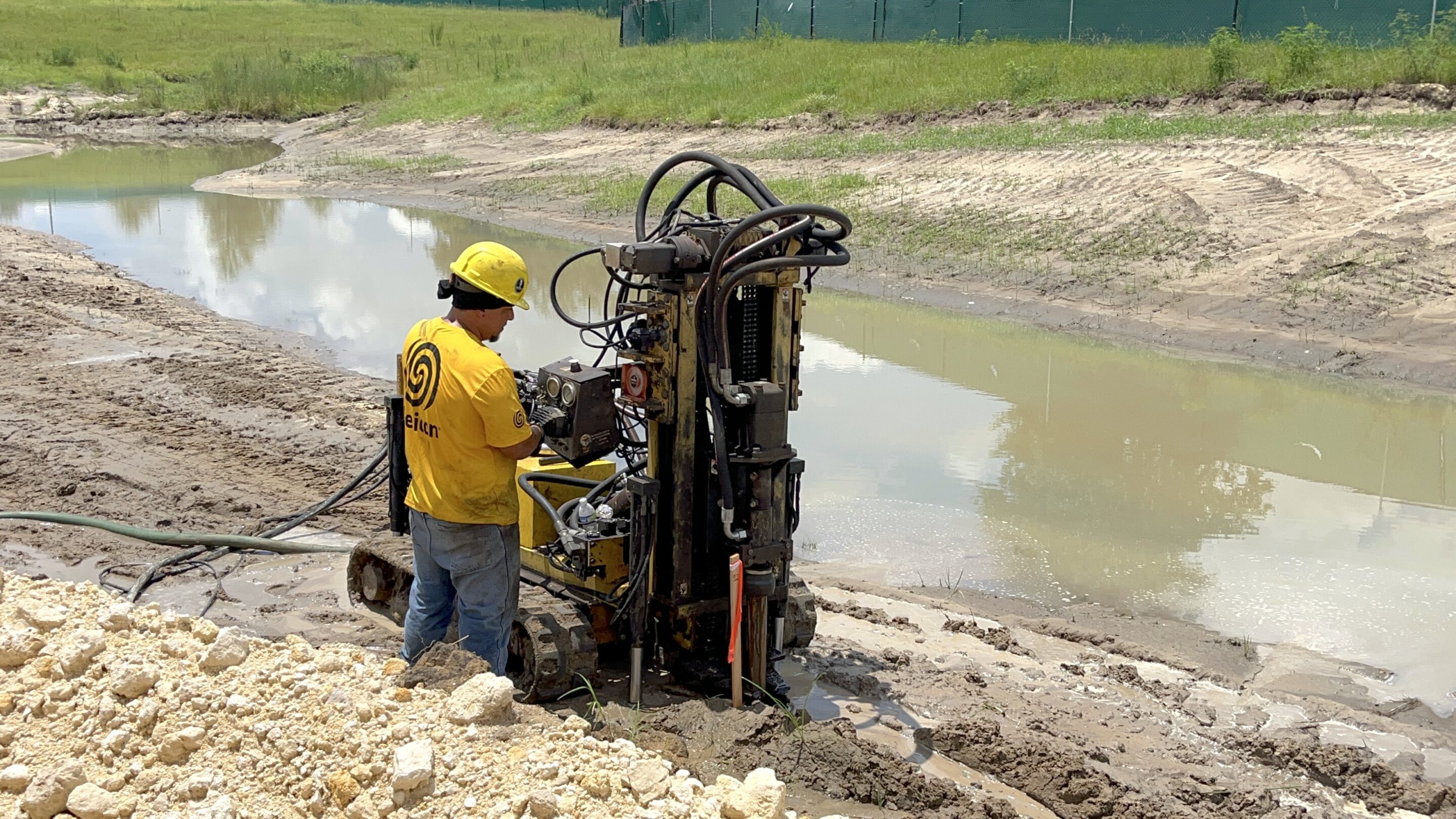 Helicon crew member drilling on compaction grout site.