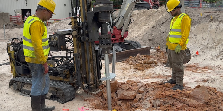 Helicon crew members inserting a helical pier into the ground.