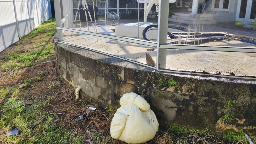 Exterior wall of a screened pool enclosure with hardened expanding foam applied inside the crack.