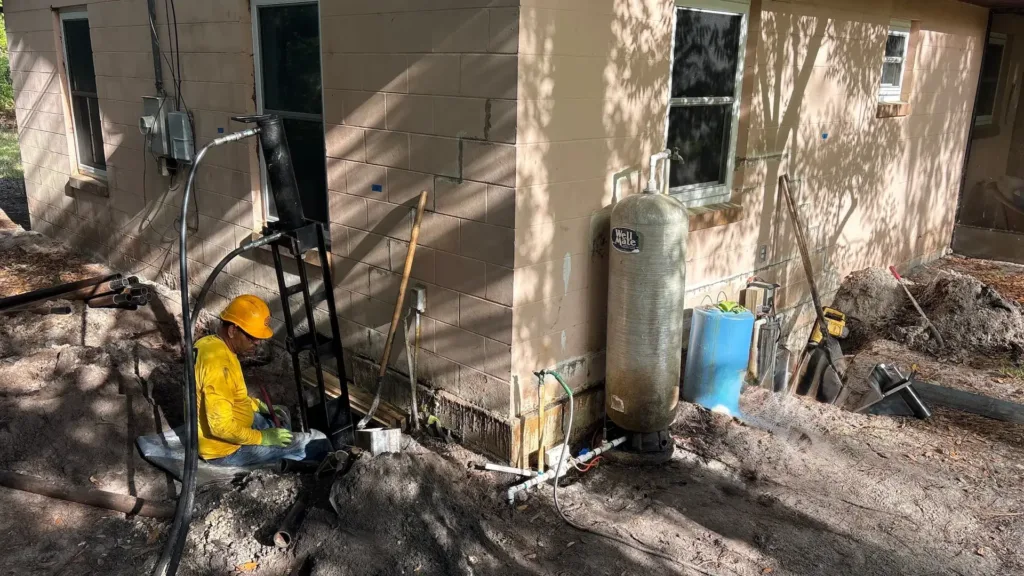 Foundation repair work in progress with a technician operating hydraulic equipment beside an excavated wall.
