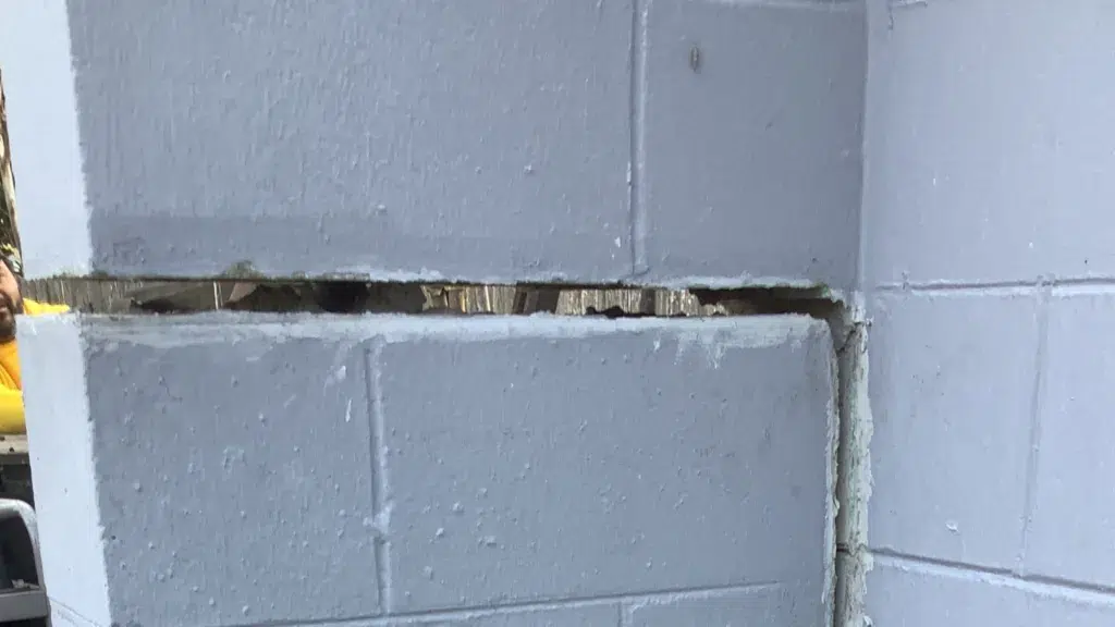 Close-up view of a large horizontal crack separating concrete block courses in a residential foundation wall, showing visible structural movement and mortar failure.