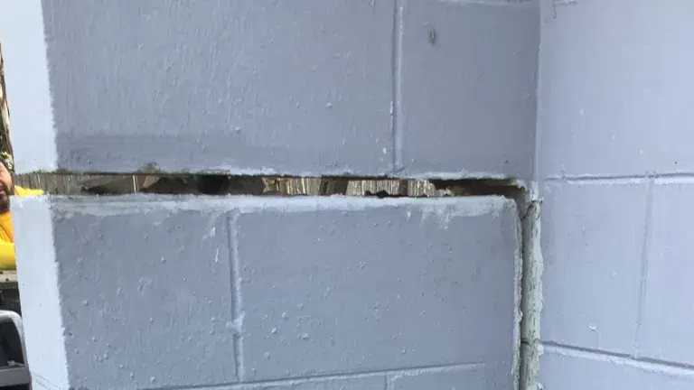 Close-up view of a large horizontal crack separating concrete block courses in a residential foundation wall, showing visible structural movement and mortar failure.