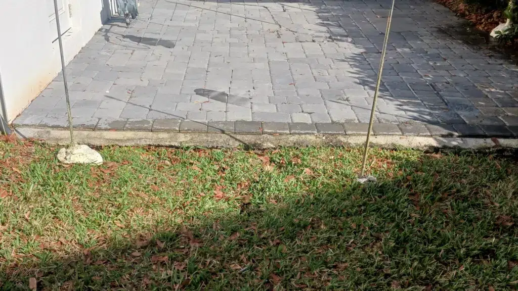 Residential concrete leveling preparation showing injection rods installed beneath a paver driveway to stabilize and lift the slab using polyurethane foam.